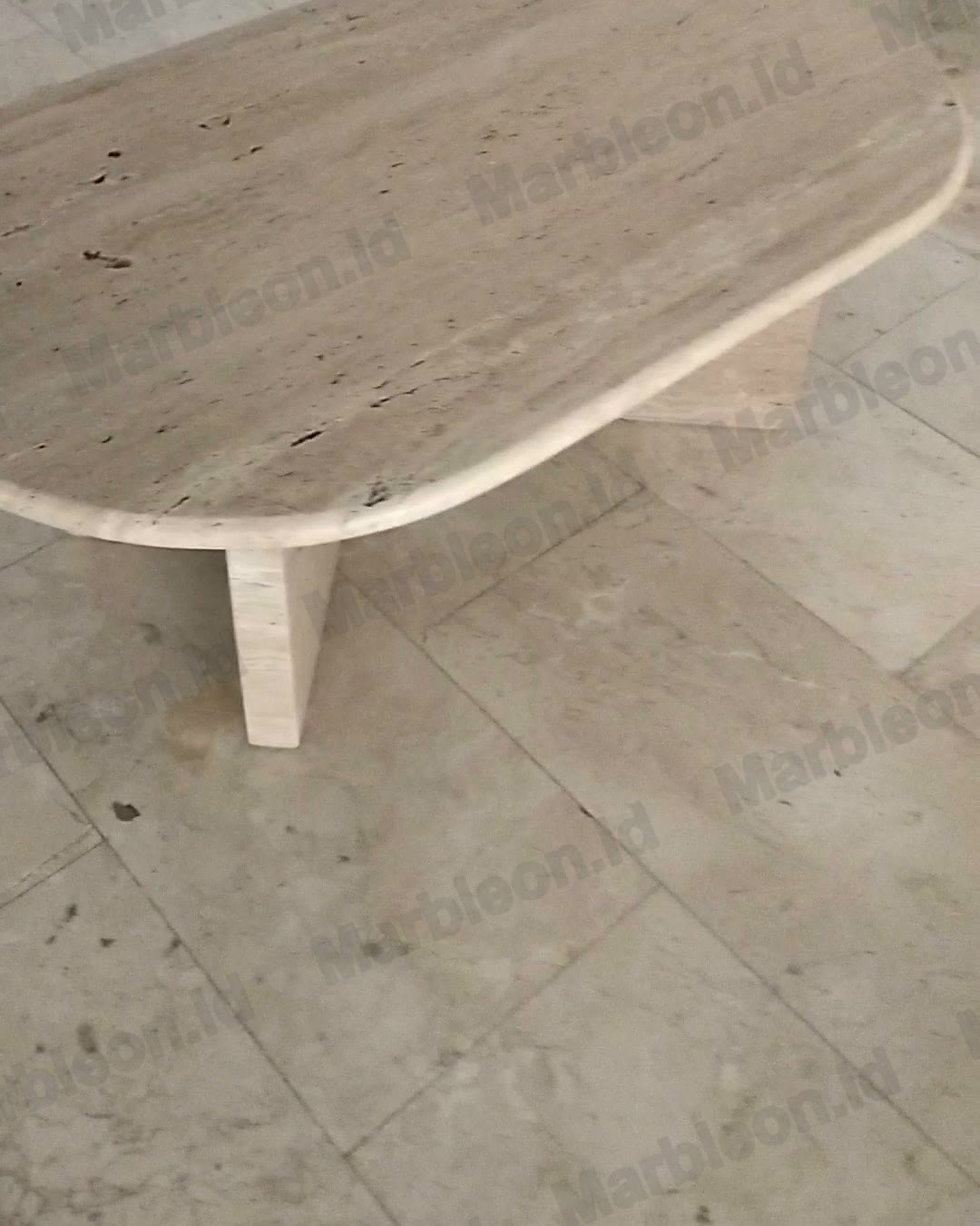 Meja oval travertine krem dengan tepi membulat dan kaki lempengan batu