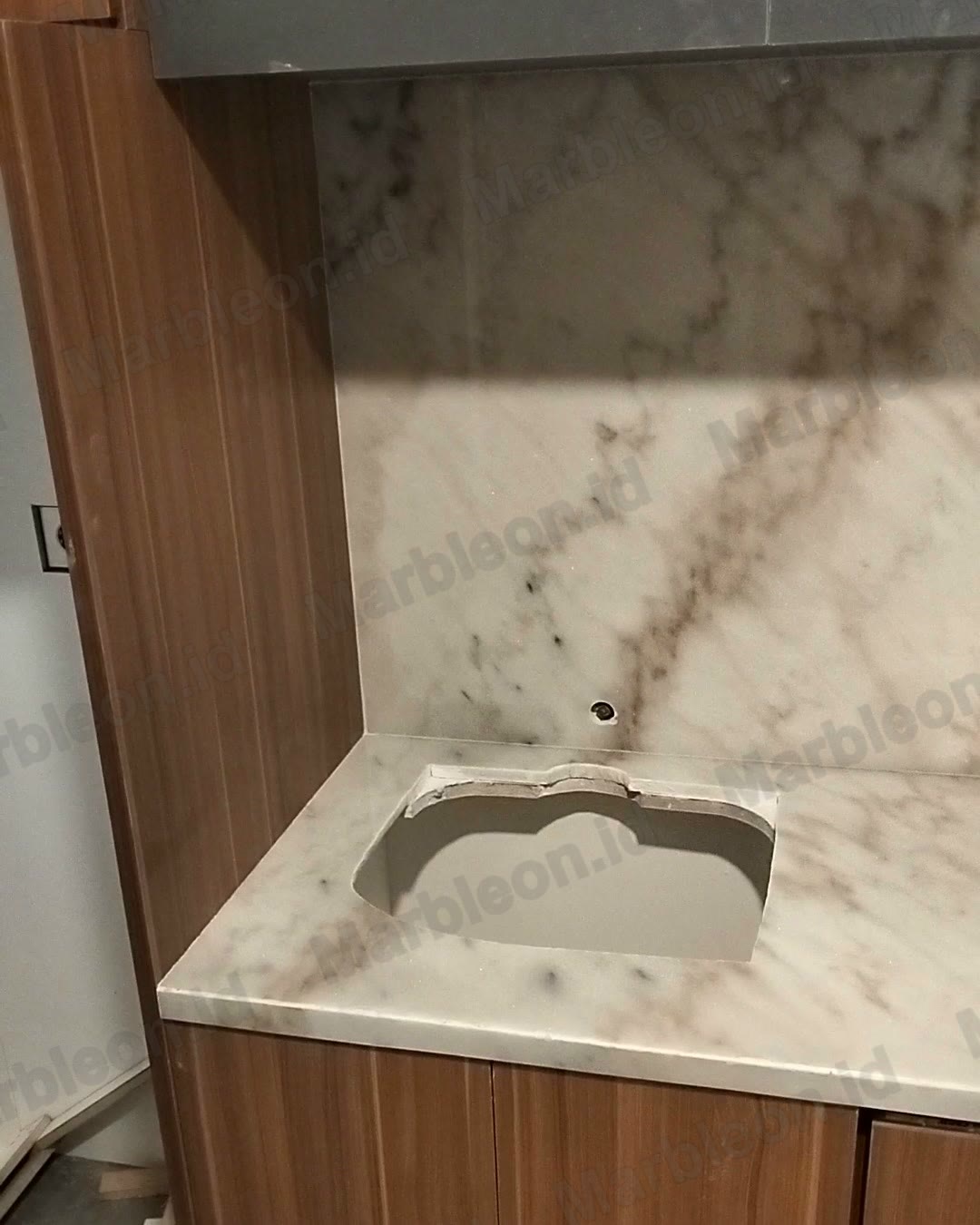 Top wastafel dan dinding marmer putih berurat cokelat keemasan di atas kabinet kayu